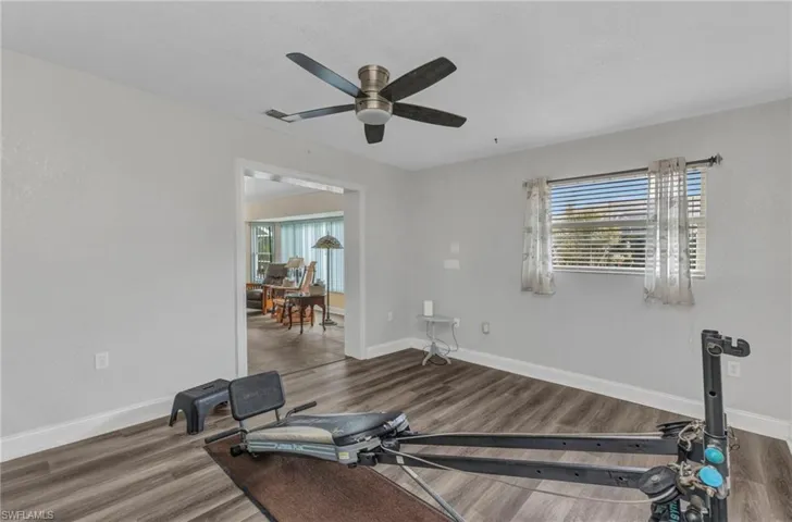 Workout area featuring ceiling fan, visible vents, baseboards, and wood finished floors