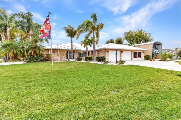 Single story home with a carport, an attached garage, concrete driveway, and a front lawn