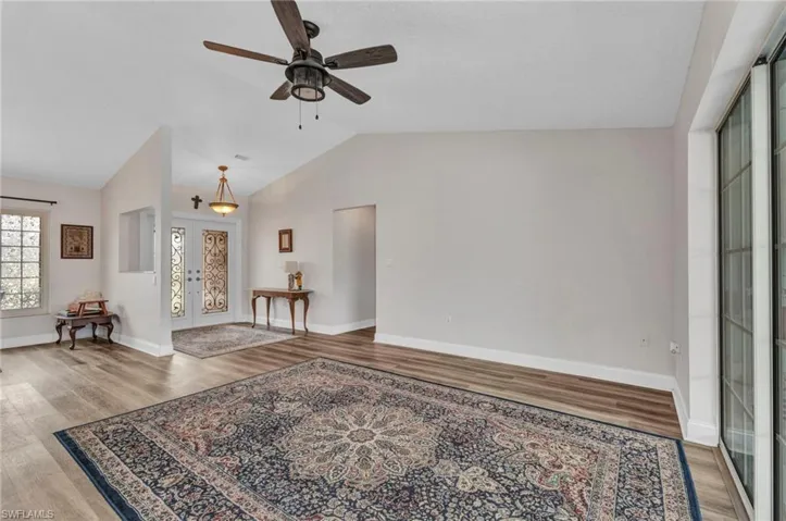 Living area featuring french doors, baseboards, wood finished floors, and vaulted ceiling