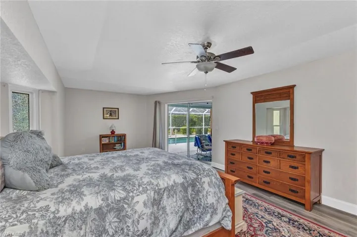 Bedroom featuring a ceiling fan, a textured ceiling, wood finished floors, baseboards, and access to exterior