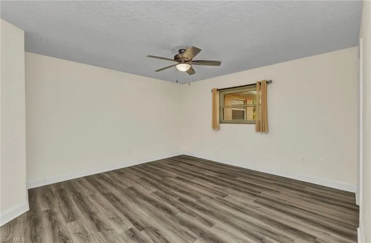 Unfurnished room with dark wood finished floors, baseboards, and a ceiling fan