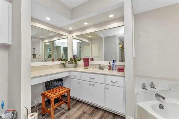 Bathroom with a bath, recessed lighting, vanity, and wood finished floors