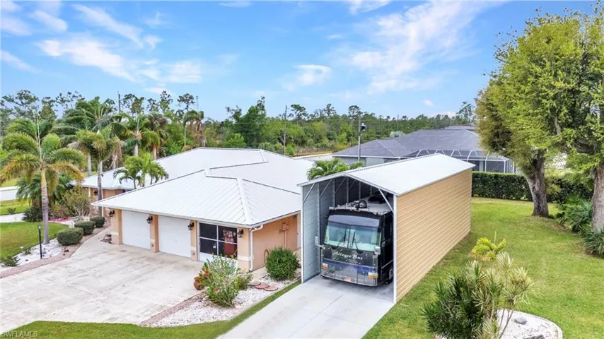 View of front facade featuring a front yard, concrete driveway, a carport, and a garage
