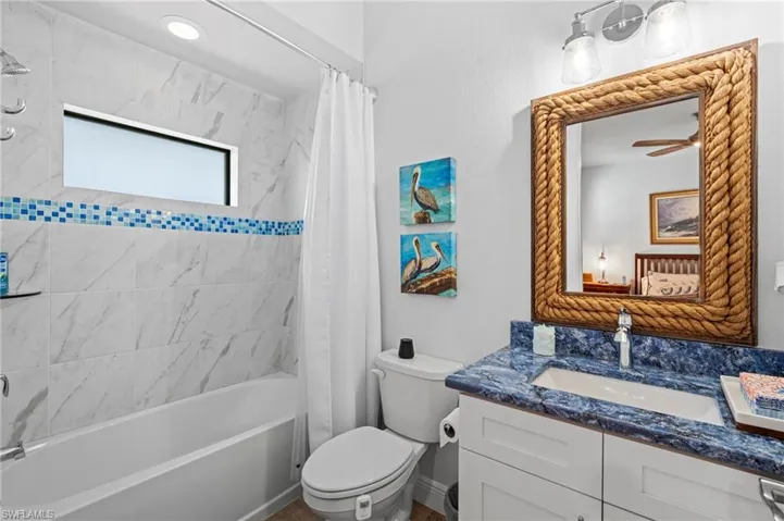 Full bathroom with shower / tub combo, vanity, toilet, and ceiling fan