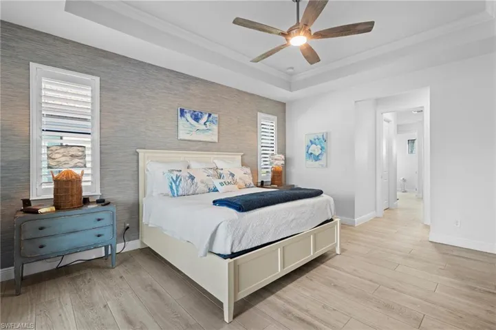 Bedroom with crown molding, a tray ceiling, and light hardwood / wood-style flooring