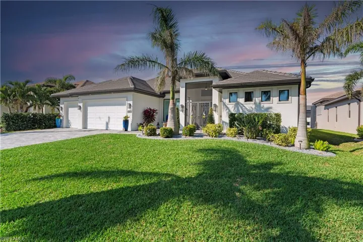 View of front facade with a tile roof, a front yard, driveway, stucco siding, and an attached garage