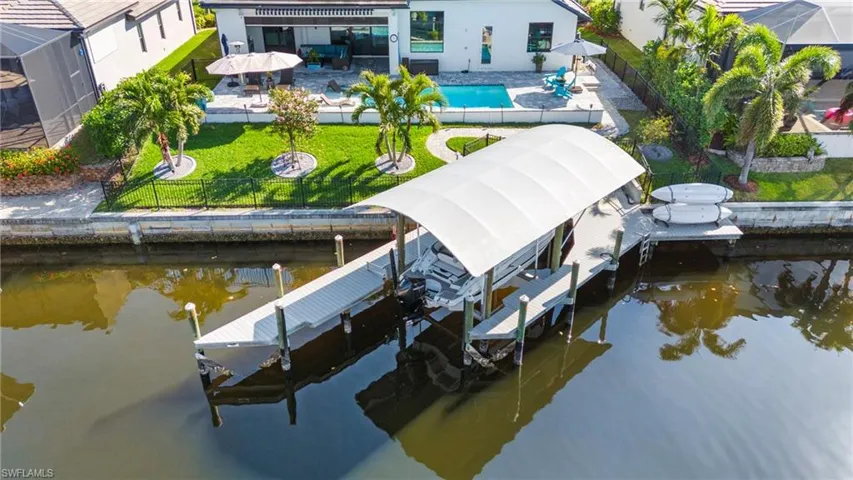 Dock area with a fenced in pool, a patio, a water view, and a yard