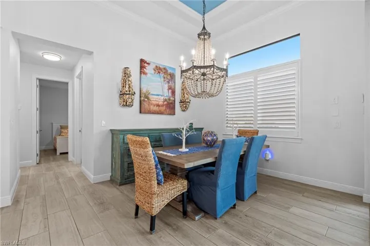 Dining area with ornamental molding, an inviting chandelier, and light hardwood / wood-style floors