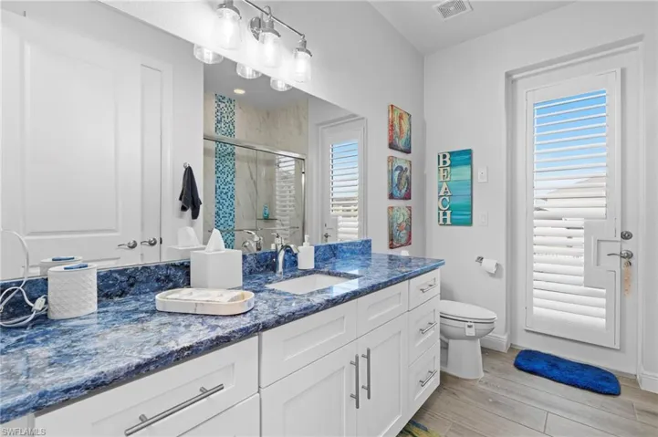 Bathroom featuring toilet, hardwood / wood-style floors, vanity, and a shower with shower door