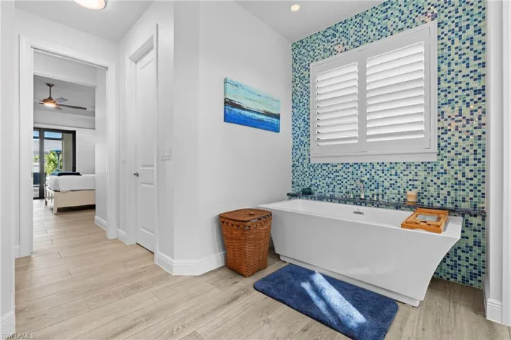 Bathroom with ceiling fan, hardwood / wood-style floors, and a washtub
