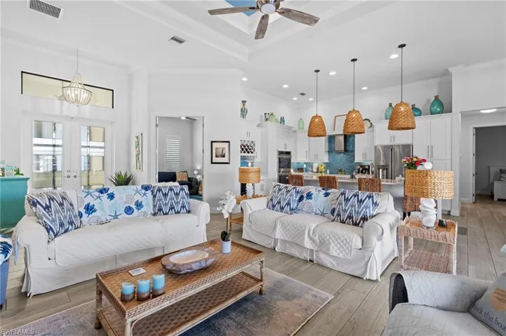 Living room featuring crown molding, light hardwood / wood-style floors, french doors, and a high ceiling
