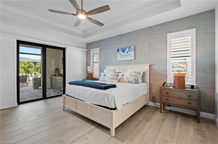 Bedroom featuring crown molding, a tray ceiling, access to exterior, and light wood-type flooring