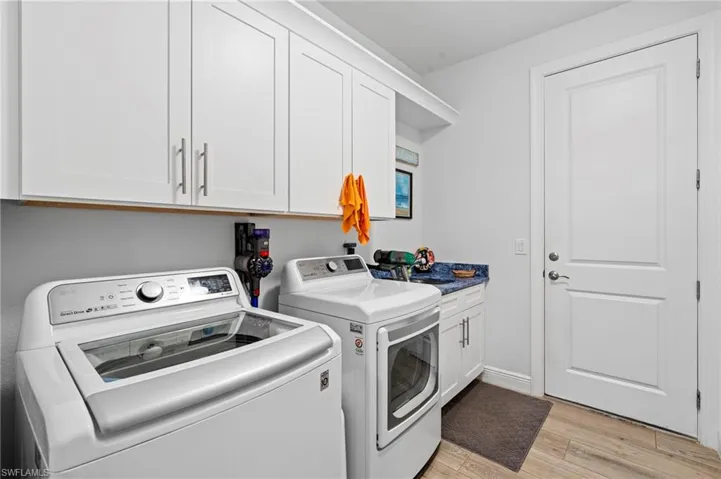 Laundry room with sink, light hardwood / wood-style flooring, washing machine and dryer, and cabinets