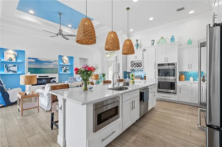 Kitchen with stainless steel appliances, sink, a center island with sink, and white cabinets