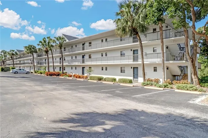 View of property with uncovered parking and stairs