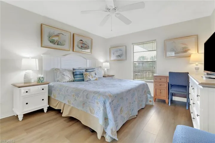 Bedroom featuring light wood finished floors, an office area, and a ceiling fan