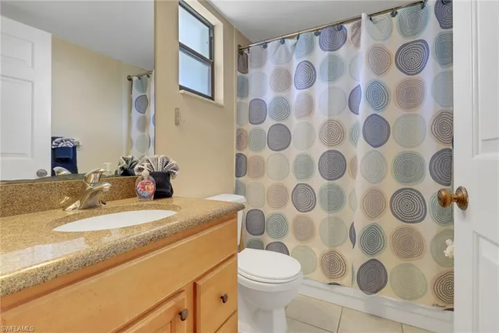 Full bathroom featuring tile patterned flooring, toilet, vanity, and curtained shower