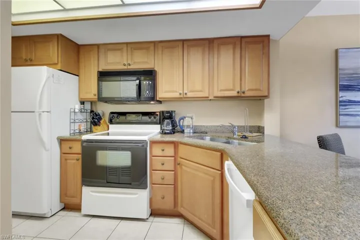 Kitchen featuring white appliances, a sink, and light tile patterned floors