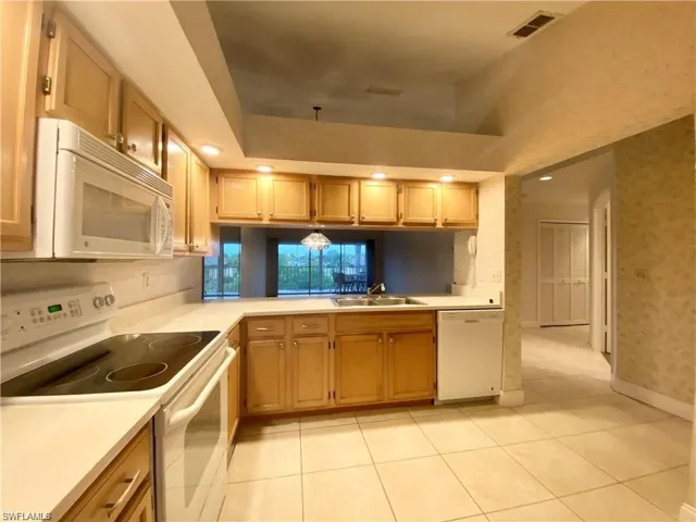 Kitchen with white appliances, light countertops, recessed lighting, light tile patterned floors, and wallpapered walls