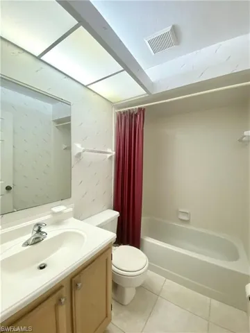 Full bath featuring shower / bath combo, vanity, and light tile patterned floors