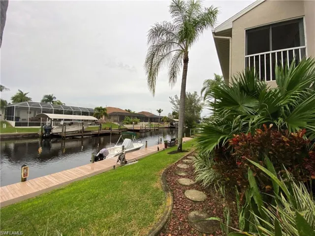 Dock area featuring a water view, a lawn, and a residential view