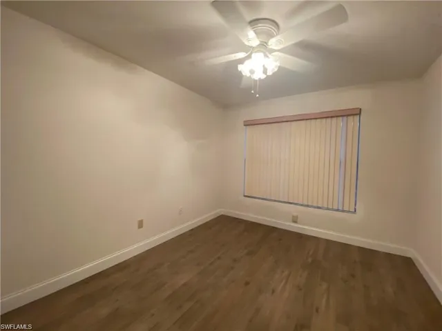 Unfurnished room with dark wood-style flooring and ceiling fan