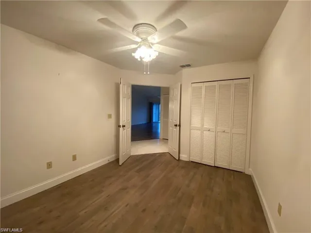 Unfurnished bedroom with dark wood finished floors, a closet, and a ceiling fan