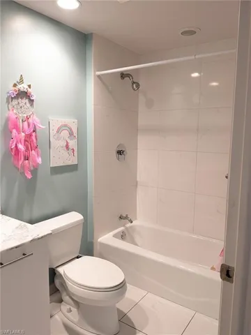Full bathroom with tile patterned flooring, vanity, toilet, and tiled shower / bath combo