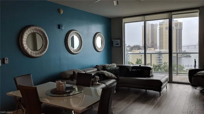 Living room with hardwood / wood-style flooring, a water view, and a wall of windows