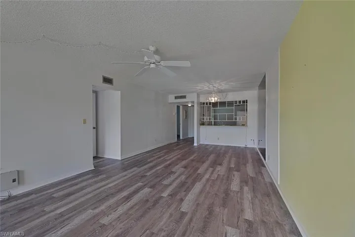 Unfurnished living room with ceiling fan, a textured ceiling, and hardwood / wood-style floors