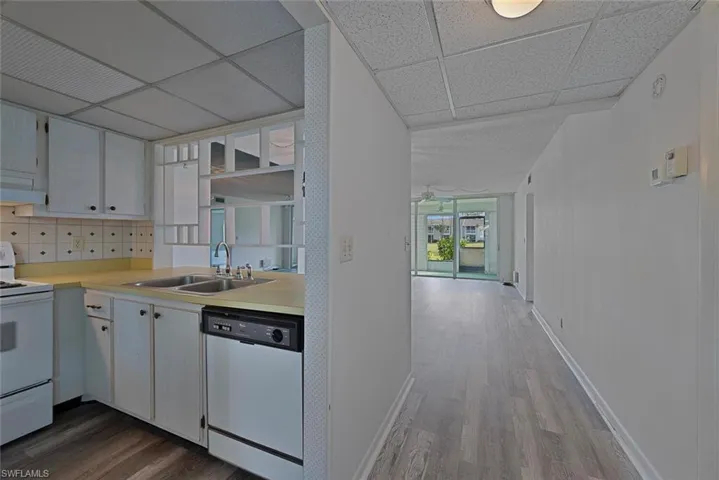 Kitchen featuring tasteful backsplash, a paneled ceiling, dishwasher, white range with electric cooktop, and sink