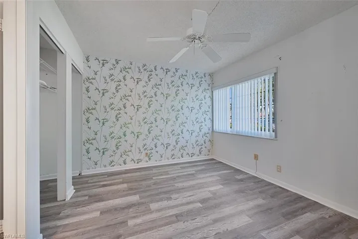 Unfurnished bedroom with ceiling fan, light hardwood / wood-style floors, a textured ceiling, and a closet