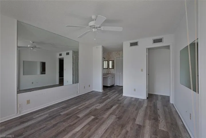 Unfurnished living room featuring a textured ceiling, dark wood-type flooring, and ceiling fan
