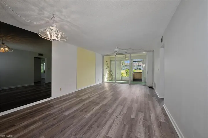 Spare room with a textured ceiling, ceiling fan with notable chandelier, and hardwood / wood-style floors