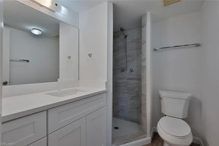 Bathroom featuring toilet, vanity, and a tile shower