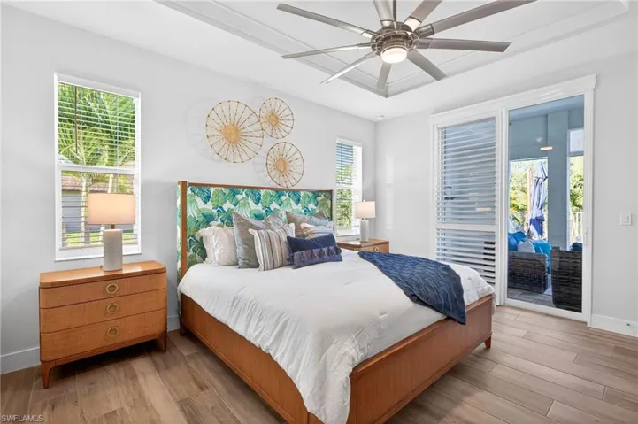 Bedroom featuring light wood-style flooring, access to outside, a ceiling fan, and a raised ceiling