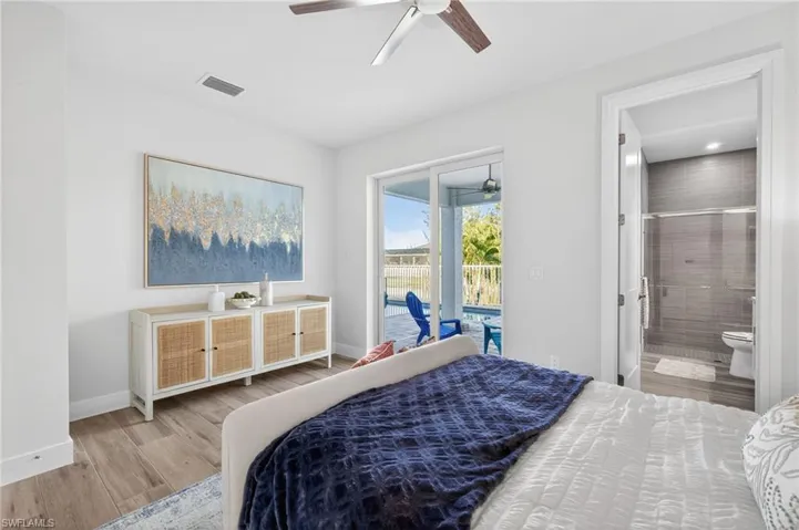 Bedroom featuring light wood finished floors, access to outside, a ceiling fan, and connected bathroom