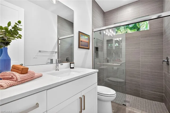 Full bath with vanity, a shower stall, and light wood-style flooring