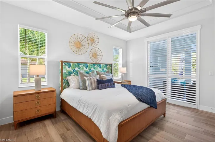 Bedroom featuring wood finished floors, ceiling fan, and a tray ceiling