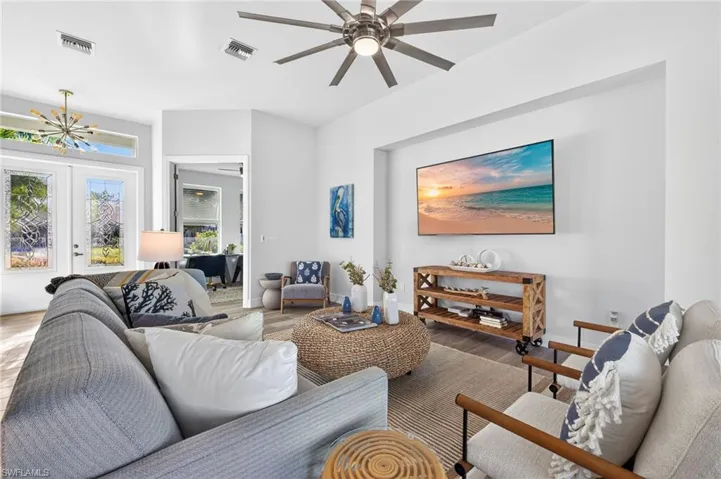 Living room with french doors, a ceiling fan, wood finished floors, and hanging lights