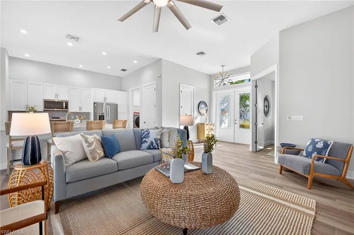 Living area featuring light wood-type flooring, ceiling fan, french doors, and suspended lighting