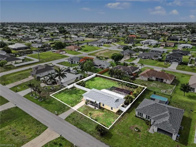 Aerial perspective showcasing the property's perimeter, a residential structure, and surrounding developed areas