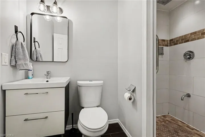 Corner vanity with integrated sink, rectangular mirror, and modern three-light fixture