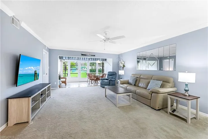 Living room with ornamental molding, carpet flooring, and a ceiling fan