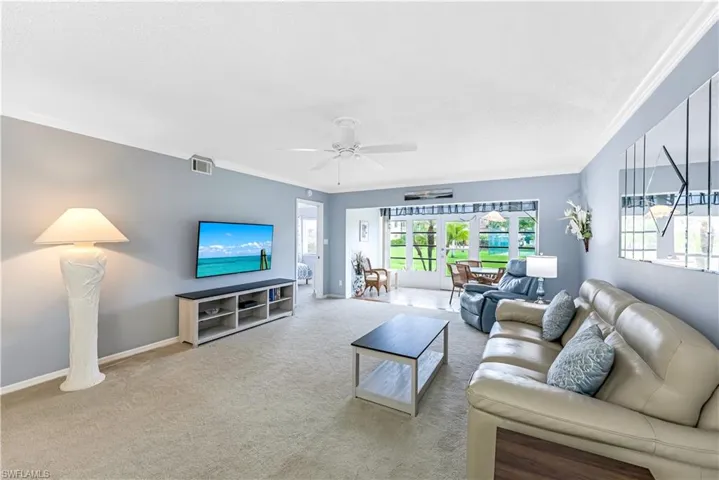 Living room with crown molding, carpet, french doors, and a ceiling fan