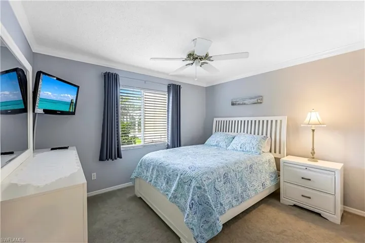 Bedroom with crown molding, light colored carpet, a textured ceiling, and ceiling fan