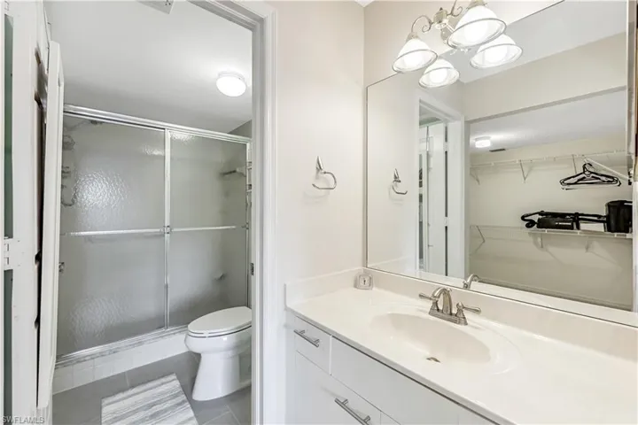 Bathroom featuring vanity, a stall shower, tile patterned flooring, a chandelier, and a spacious closet