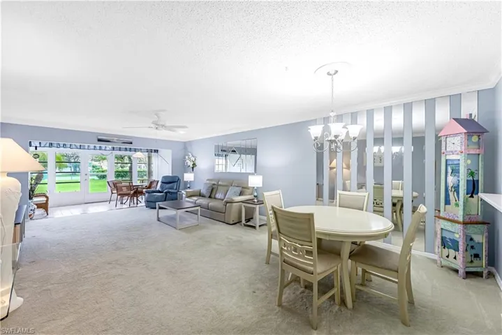 Dining area featuring ceiling fan, light colored carpet, ornamental molding, a textured ceiling, and french doors