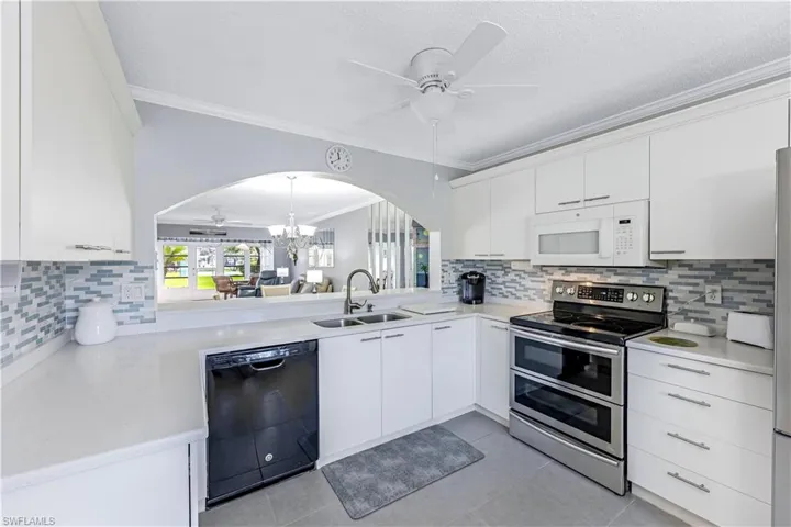 Kitchen featuring tasteful backsplash, a ceiling fan, range with two ovens, crown molding, and a chandelier