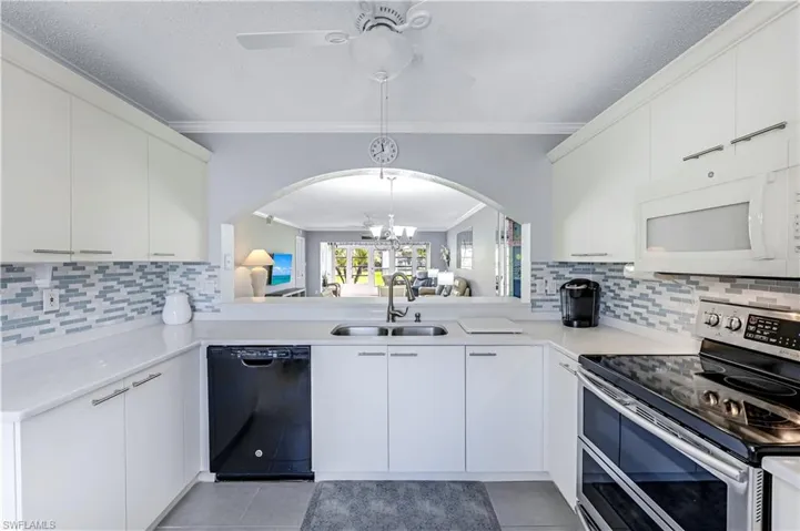 Kitchen featuring tasteful backsplash, range with two ovens, a chandelier, crown molding, and white microwave